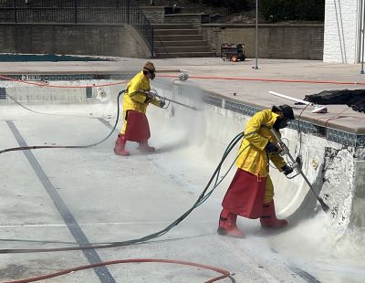a crew prepares the surface of a pool