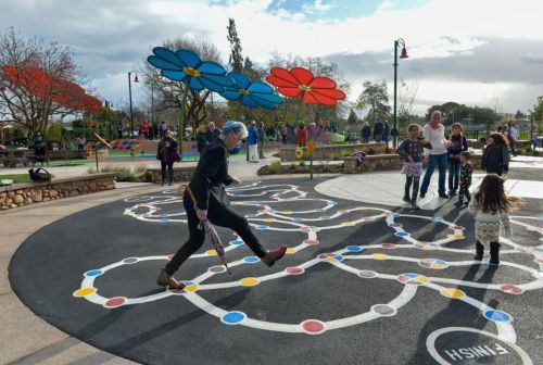 adults and children in a play space with flower-shaped shade elements in the background
