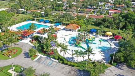 an overhead view of an aquatic facility with palm trees and a parking lot