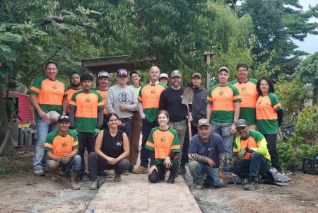 volunteers pose for a group photo with a path and greenery and one shovel