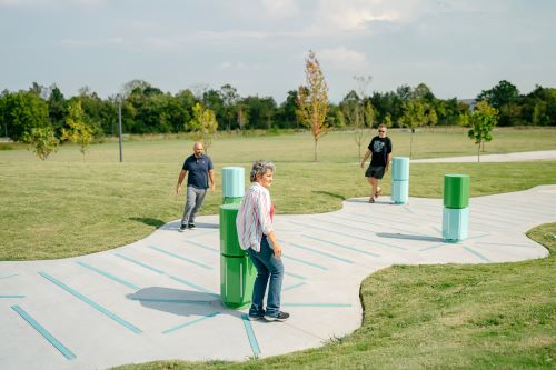 people walk amongst the bollards of an interactive display in a park