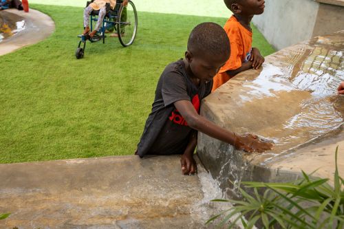 a child touches water flowing over a rock