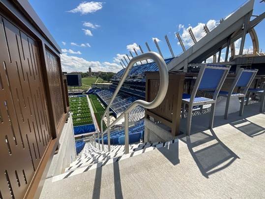 a view of a football field showing stairs, railing and seating