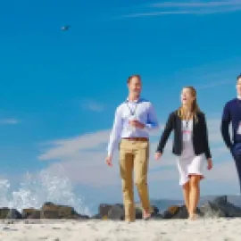 Three meeting attendees walking on the beach